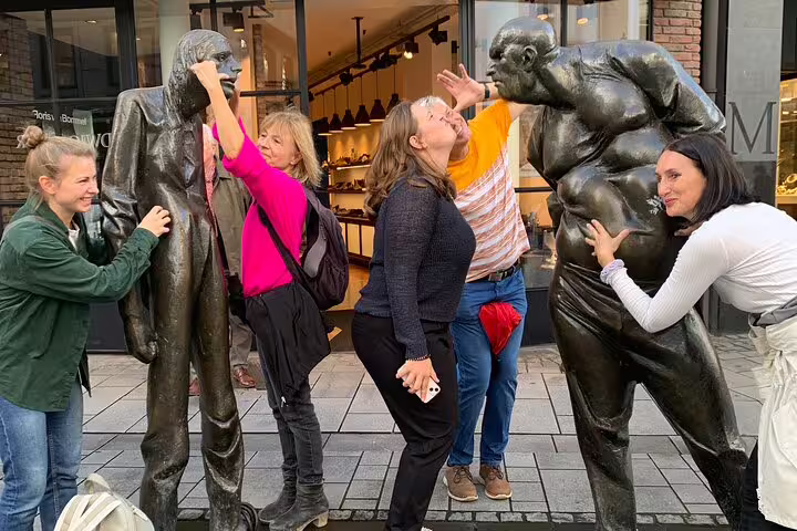 Group interacting with bronze sculptures on Düsseldorf scavenger hunt, fun photo stop on self-guided tour