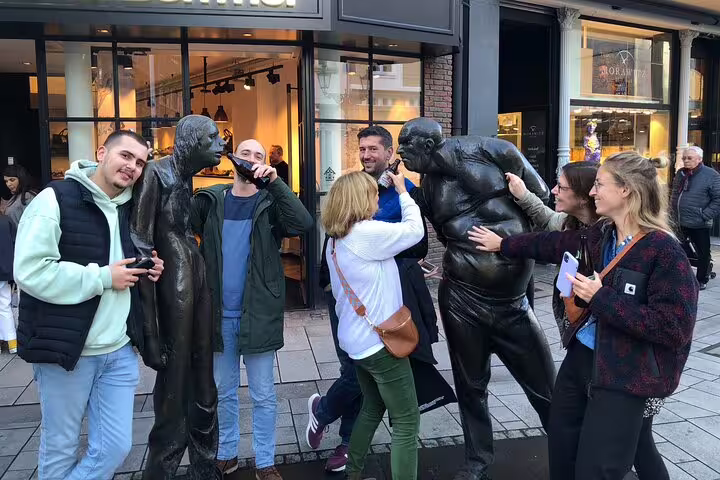 Participants laughing with bronze statues on Düsseldorf self-guided scavenger hunt and city sights walking tour