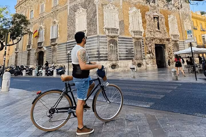 Man with Dutch-style Omafiets city bike rental outside ornate historic building in Valencia, ideal for easy sightseeing