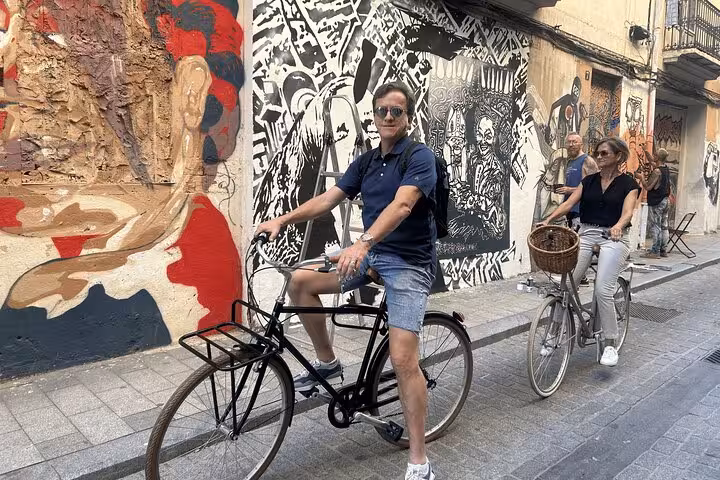 Riders on Dutch-style omafiets city bikes pass street art murals on a self-guided bike rental route
