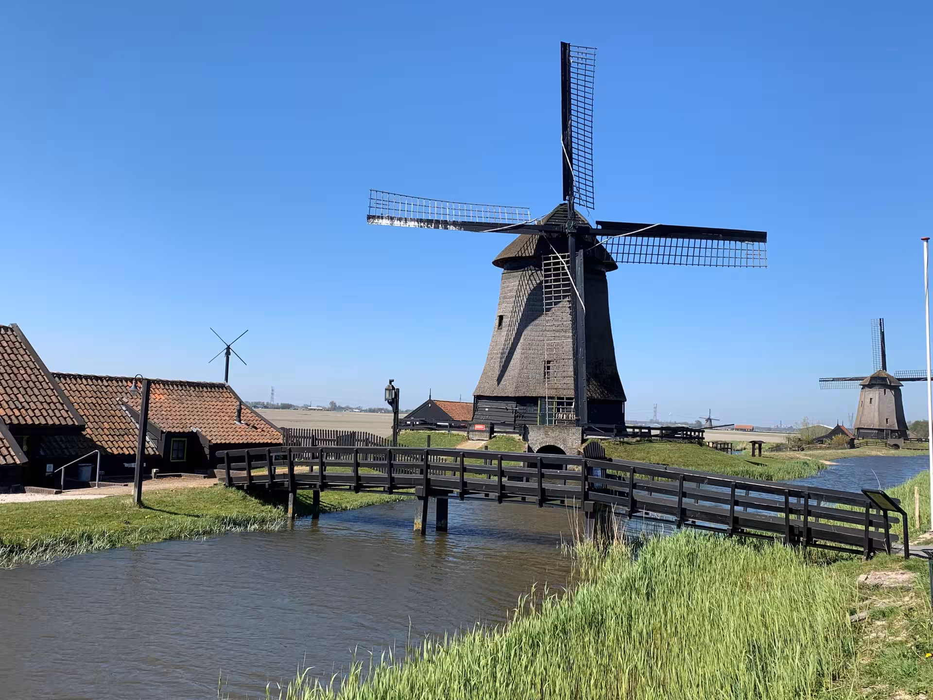 Traditional Dutch windmill by canal and footbridge, classic countryside stop on private tour from Leiden
