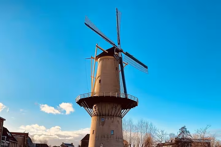 Traditional Dutch windmill under blue sky on private Rotterdam day tour to historic towns, mills and castle