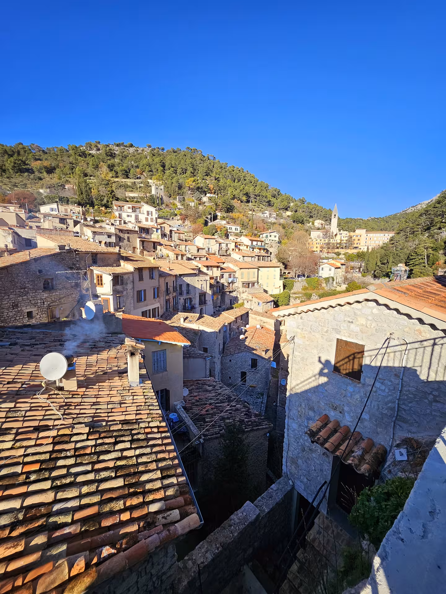 Scenic view of a picturesque hilltop village in East Côte d'Azur with traditional stone houses and lush greenery.
