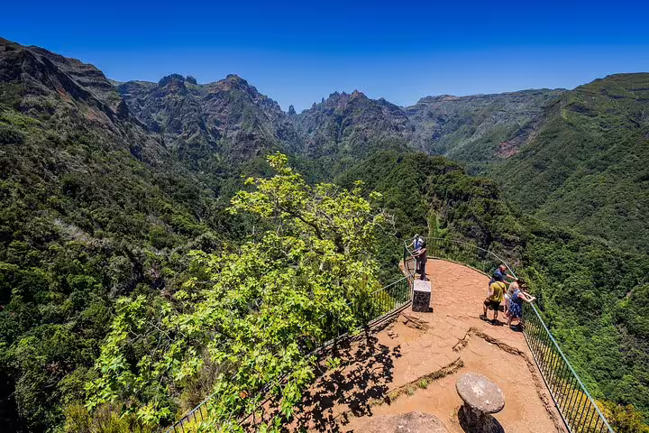 Tourists enjoy breathtaking views from a scenic lookout surrounded by lush mountains on the East Madeira Tour.