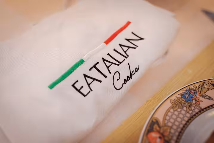 Close-up of an apron with 'Eatalian Cooks' logo, highlighting an authentic Italian cooking class in Rome.