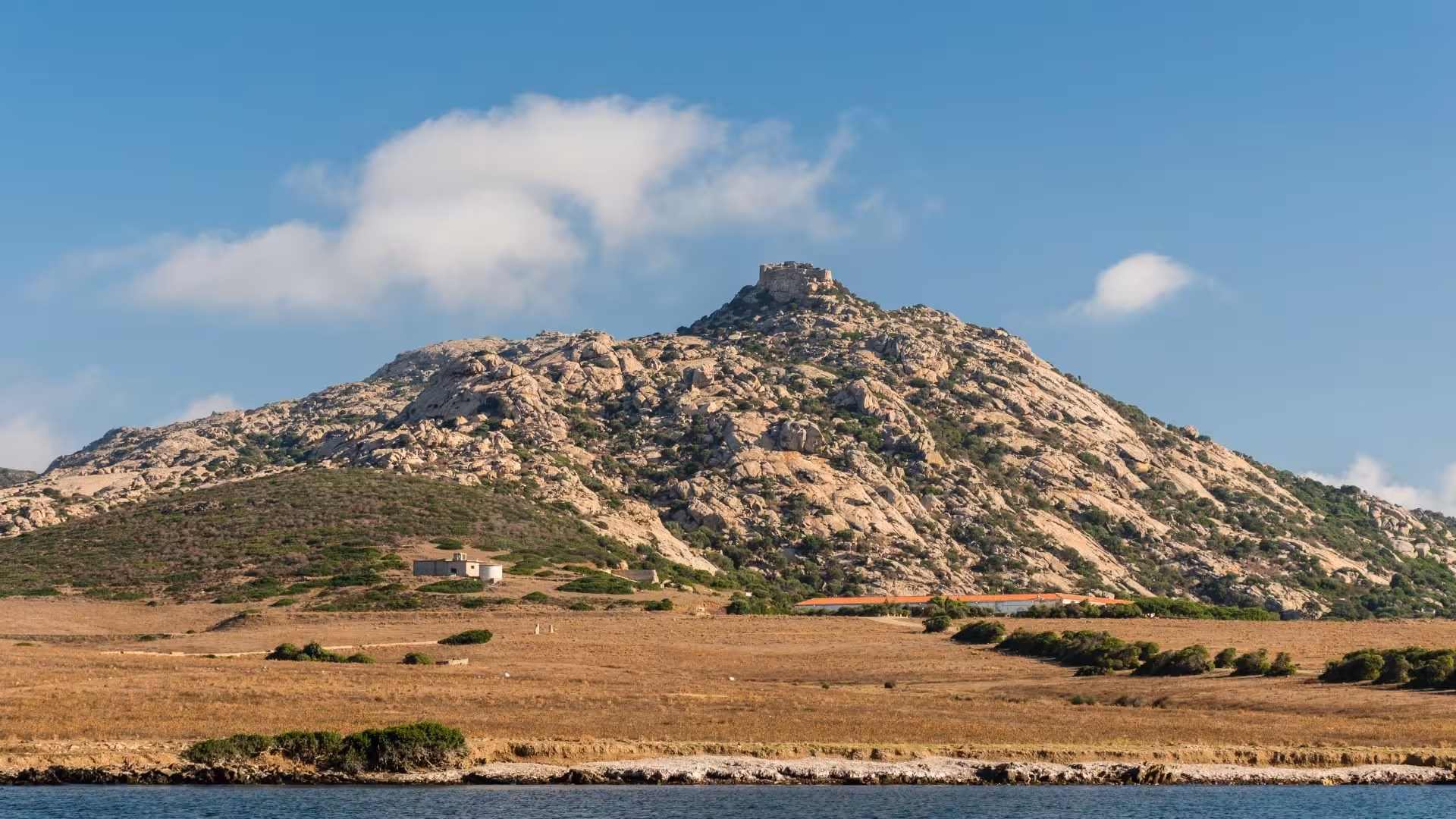 Scenic view of rocky hill and ancient ruins on Asinara Island, perfect for e-bike exploration from Porto Torres.