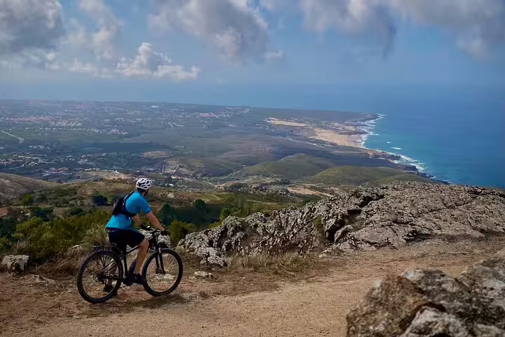 E-biker explores breathtaking coastal views from the rugged hills of Cascais and Sintra, overlooking the vast ocean.