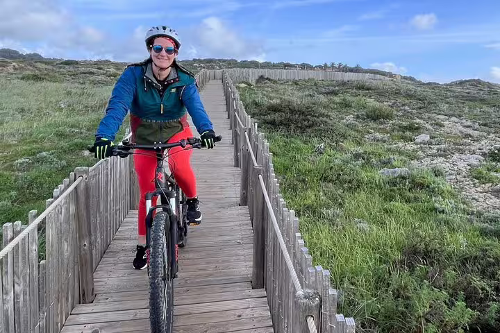 Smiling cyclist on a wooden path through lush greenery in Sintra on an e-bike tour from Lisbon to Cascais.