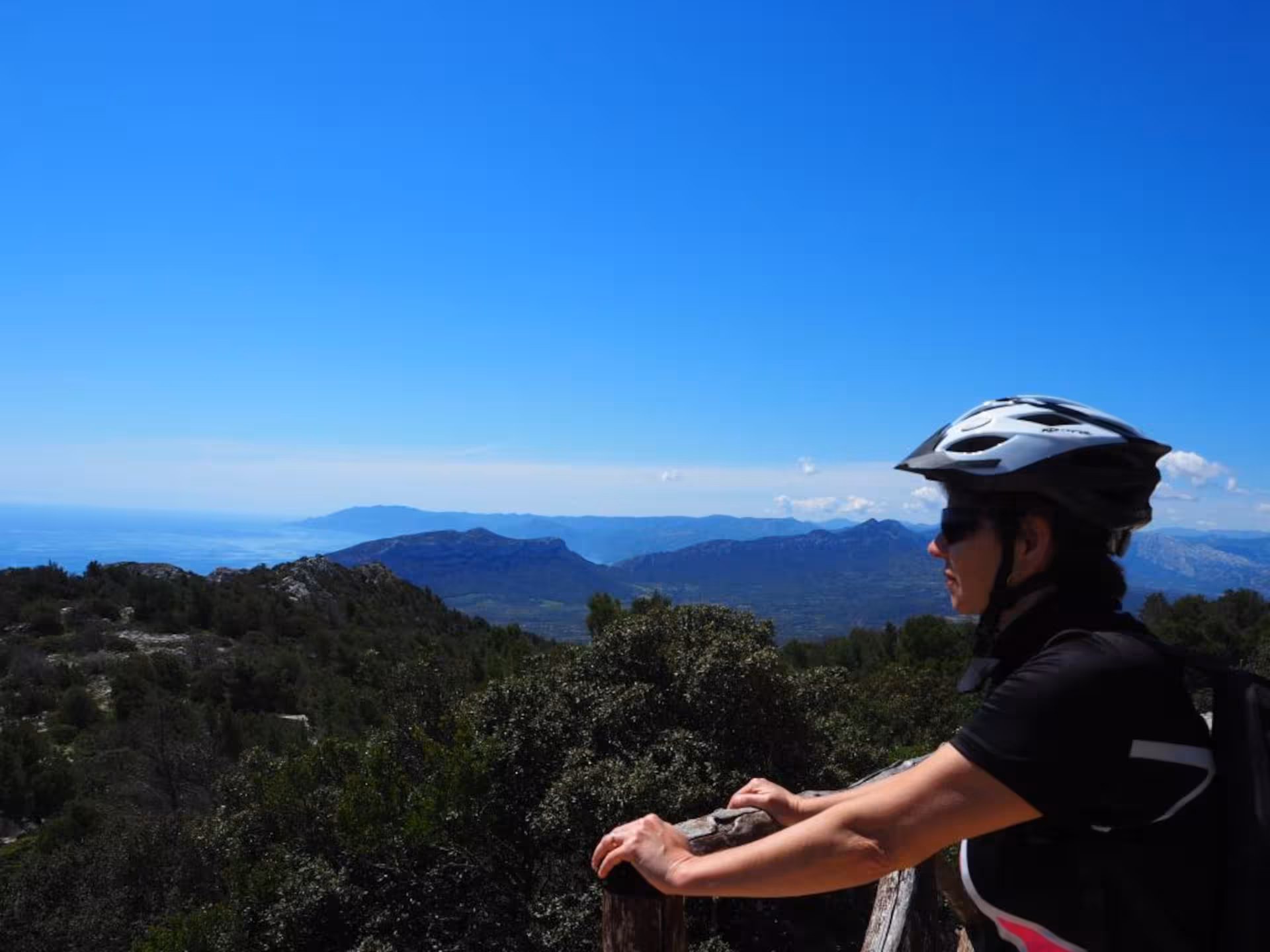 Cyclist enjoying panoramic views of Sardinia's mountains and sea on an e-bike tour.