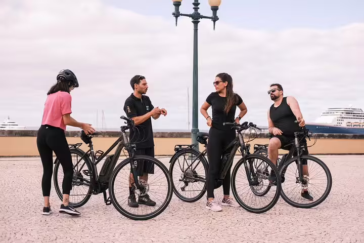 Group of cyclists enjoys a scenic e-bike road tour from Cabo Girão to Funchal, with stunning ocean views and modern bikes.