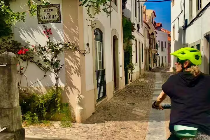 Cyclist exploring charming Sintra streets on an e-bike, surrounded by historic architecture and vibrant greenery.