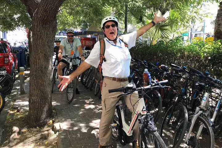 Excited tourist on an e-bike tour under the shade in Athens, ready for a cultural and culinary adventure.