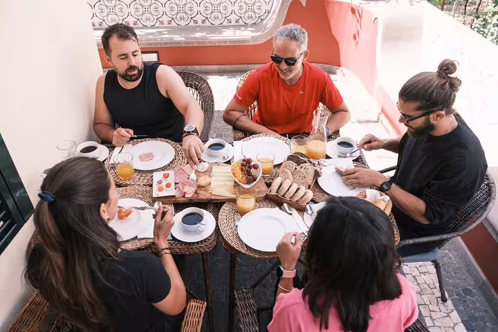 Group enjoying a scenic breakfast on the E-Bike Road Tour from Cabo Girão to Funchal with fresh pastries and coffee.
