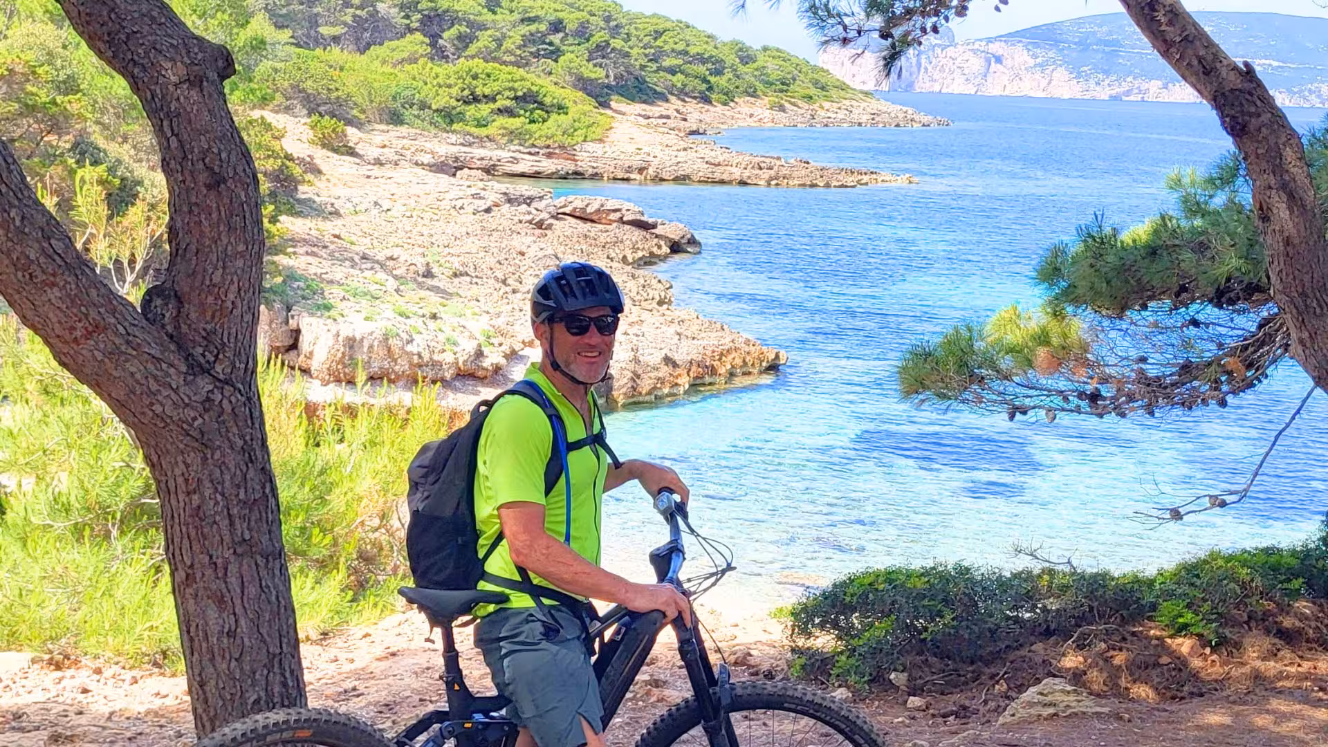 Cyclist on an e-bike exploring the scenic coastal trails of Capo Caccia in Alghero, surrounded by lush greenery.