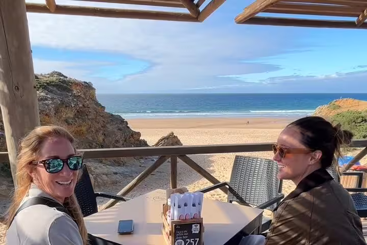 Two people enjoying drinks with stunning ocean views at a beachside café in Cascais, Portugal.