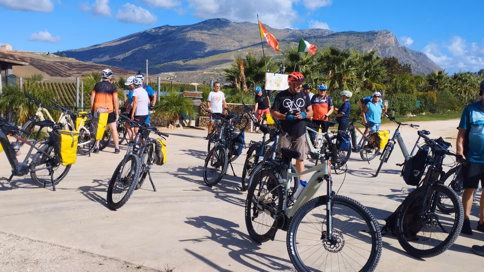 Cyclists gather with e-bikes in sunny Erice, surrounded by lush landscapes, ready for a scenic Trapani adventure.