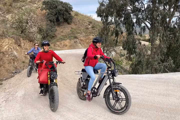 Riders on off-road e-fat bikes tackling a gravel trail in the Montes de Malaga on a guided e-bike adventure