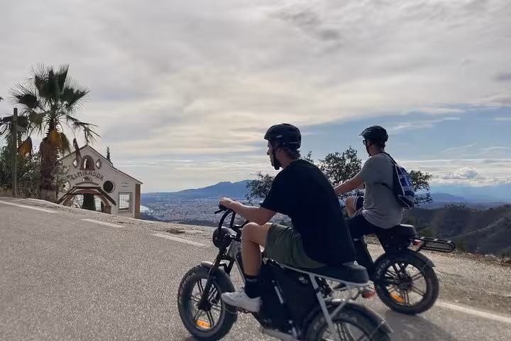 Riders on e-fat bikes climbing a scenic Malaga hillside road toward Montes viewpoint on guided e-bike tour