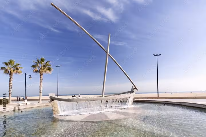 E-bike tour stop at Valencia Malvarrosa beach fountain sculpture with sea views and palm-lined promenade