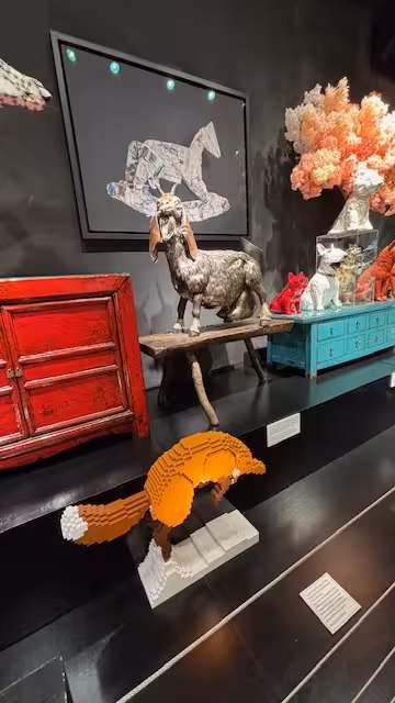 Eclectic art exhibit with animal sculptures, vibrant red furniture, and modern art pieces for sculpture tour.
