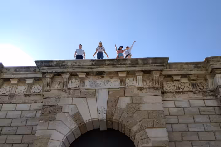 Cyclists on a historic stone arch monument during eco bike full-day tour, combining history sightseeing, food and wine