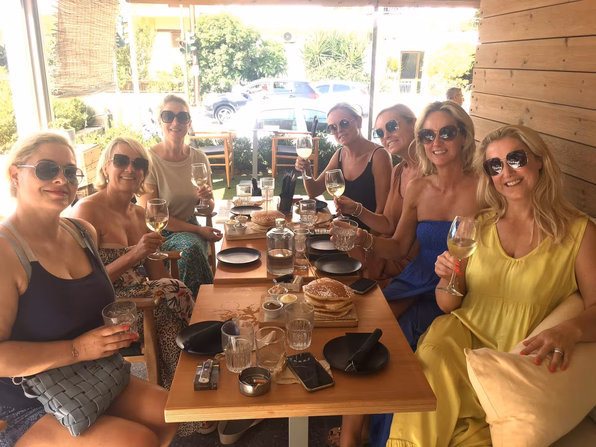 Friends enjoying white wine tasting with local snacks on an eco bike wine tour stop at a sunny terrace cafe