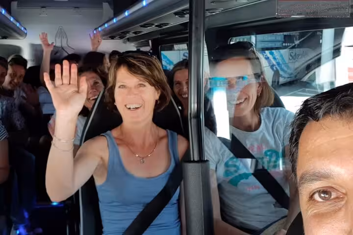 Smiling passengers waving inside a tour coach on the Glencoe and Scottish Highlands day trip from Edinburgh