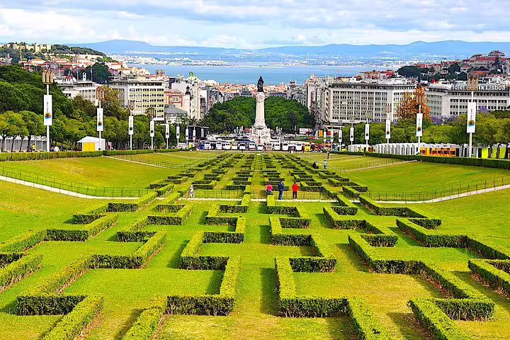 Panoramic view of Eduardo VII Park in Lisbon, showcasing its manicured hedges and the cityscape beyond.