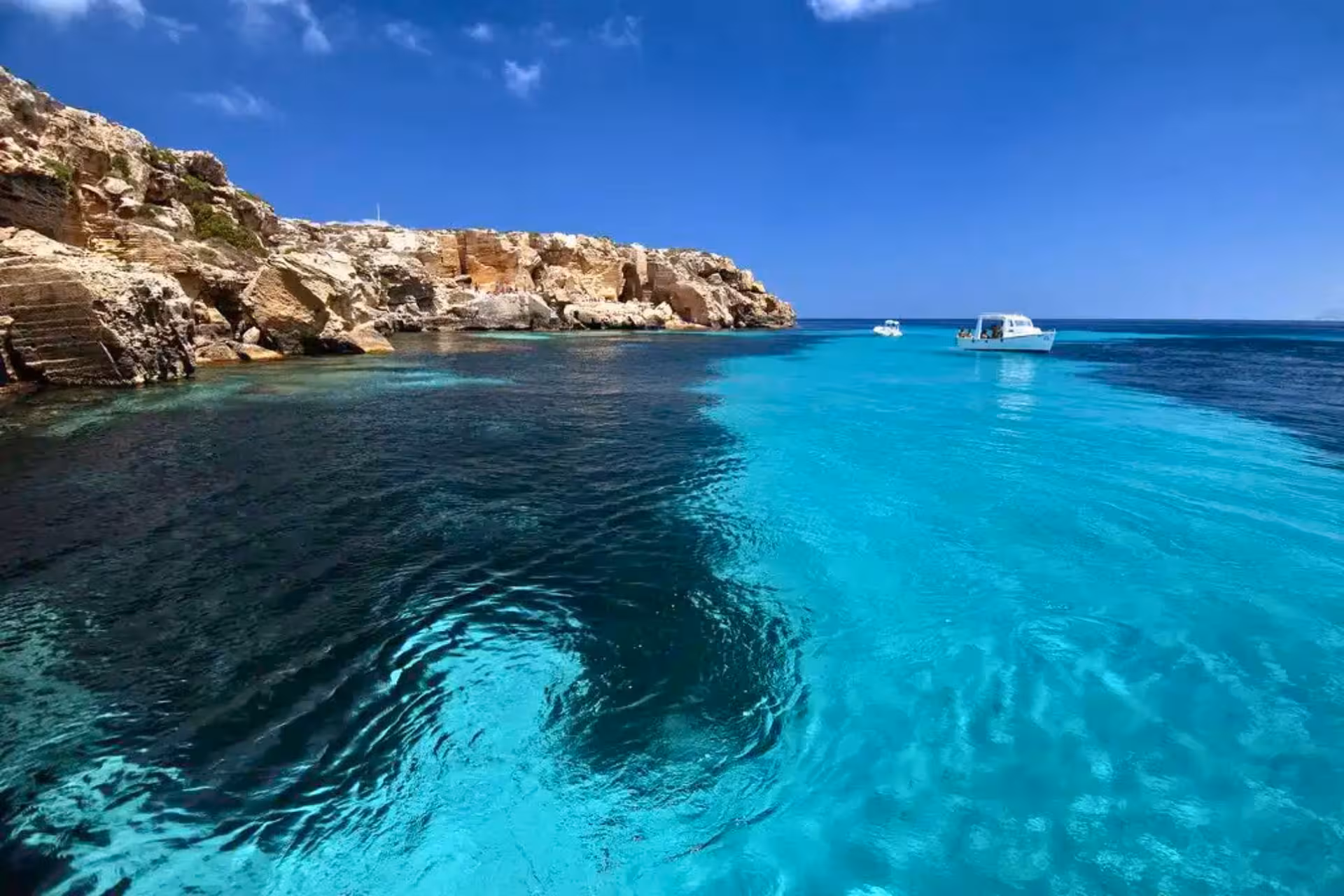 Dinghy tour in Favignana lagoon, Egadi Islands from Trapani, crystal-clear water and cliffs with boat