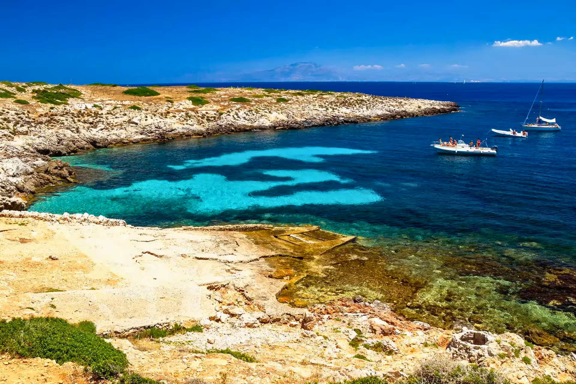 Dinghy and sailboats in a turquoise bay at Favignana on Egadi Islands private tour from Trapani with lunch