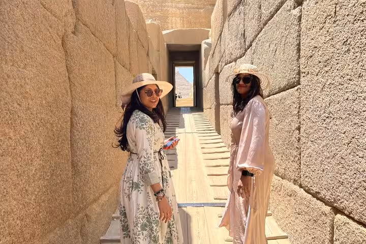 Two women exploring an ancient Egyptian corridor near the pyramids, showcasing cultural highlights of the 11-day tour.