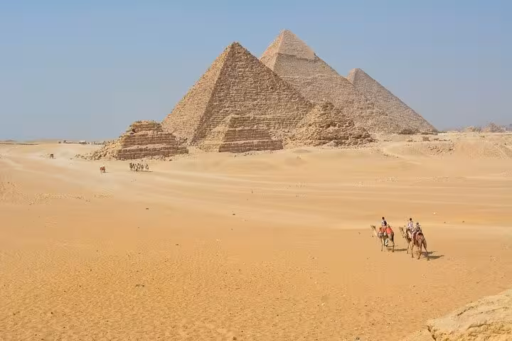 Camel riders in front of the majestic Pyramids of Giza, a highlight of the 11-day Egypt all-inclusive tour with Nile cruise.
