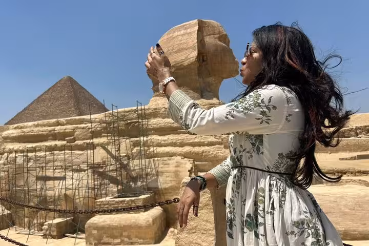 Traveler capturing a photo of the Sphinx and pyramids under a clear blue sky, highlighting the Egypt tour experience.