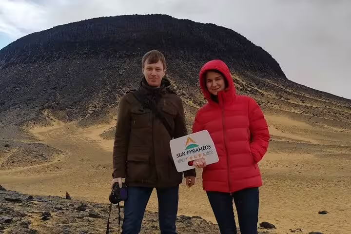 Travelers at Egypt Black Desert volcano on 2-day jeep adventure tour, posing in White Desert landscape