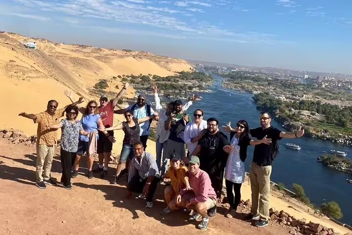 Travelers posing on desert hilltop with panoramic Nile River view in Aswan, 14-day Egypt Nile Sahara tour