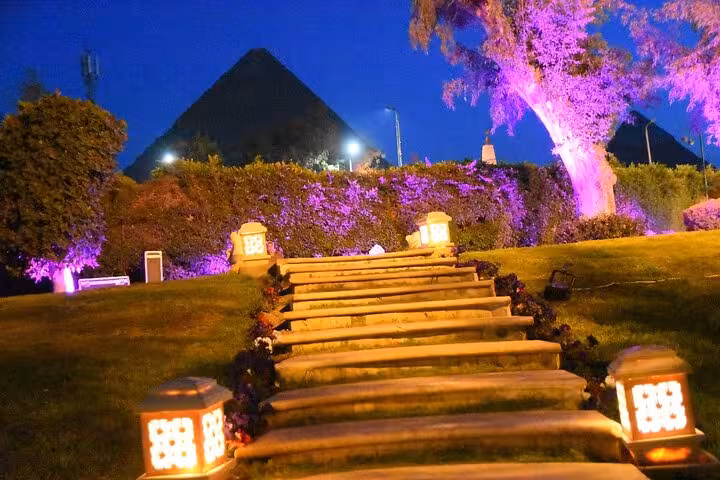 Illuminated garden pathway with a view of the Pyramids, part of the unique Egypt in 11 days all-inclusive tour.