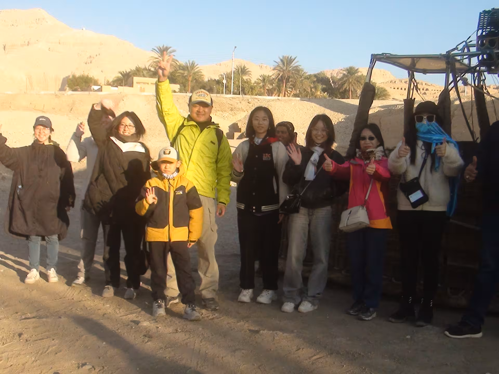 Happy tourists posing near a hot air balloon in the Egyptian desert, part of a comprehensive 15-day Egypt tour.