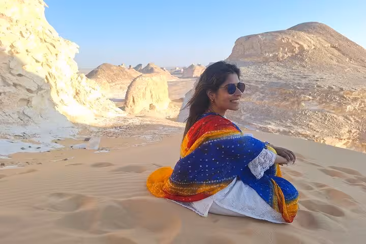 Traveler enjoys the breathtaking view of Egypt's White Desert, wrapped in vibrant colors during an all-inclusive camping tour.