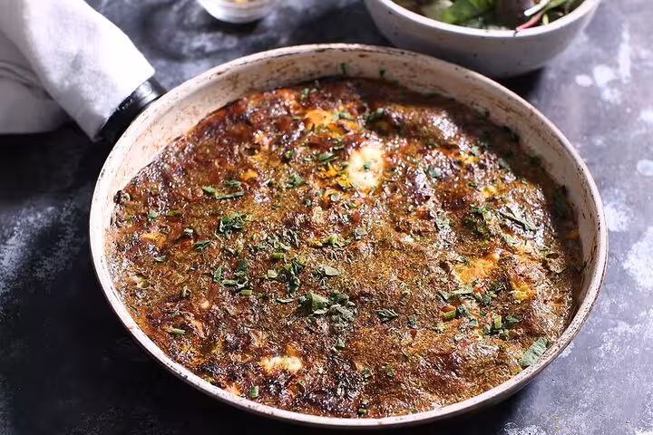 Delicious Egyptian feteer served in a pan, garnished with fresh herbs, highlighting authentic Cairo food tour flavors.
