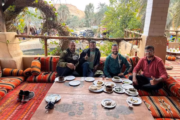 Guests share traditional Egyptian dishes on a local food and tea tour, seated on Bedouin cushions