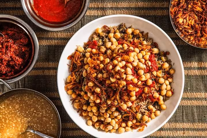 Savor a bowl of Egyptian koshari, garnished with chickpeas and crispy onions, on the Cairo food tour.
