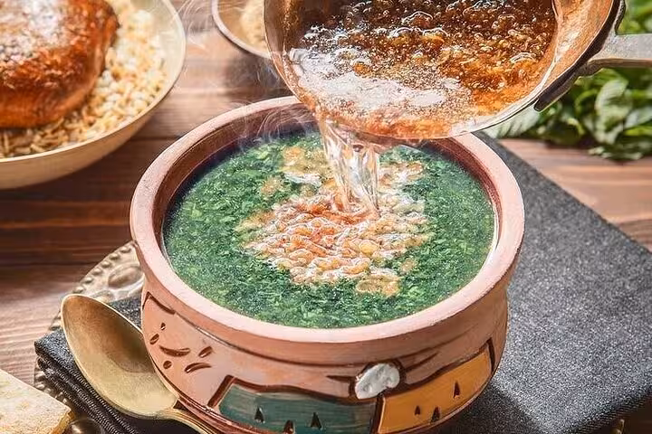 Close-up of Egyptian molokhia soup with garlic oil being poured, a must-try dish on a Cairo food and tea tour