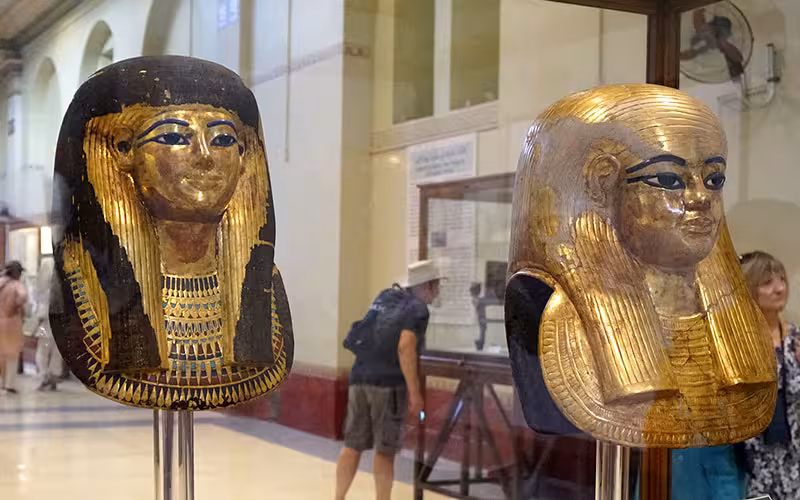 Golden ancient Egyptian mummy masks on display at Cairo Museum, must-see stop on a 1 day Cairo tour
