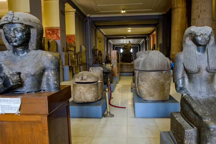 Ancient Egyptian statues and stone sarcophagi in a museum gallery on a Cairo private half-day guided tour