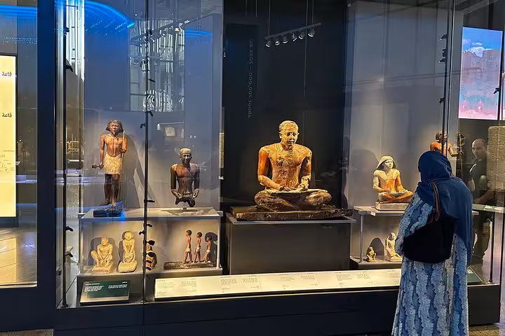 Ancient Egyptian statues in Grand Egyptian Museum gallery as visitors explore exhibits on Giza tour with lunch