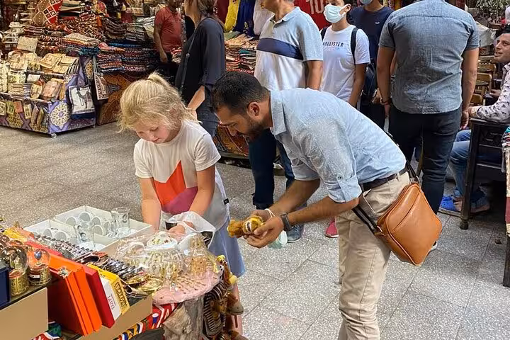 Guide showing a traveler local Egyptian sweets at a bustling bazaar during a traditional food and tea tour