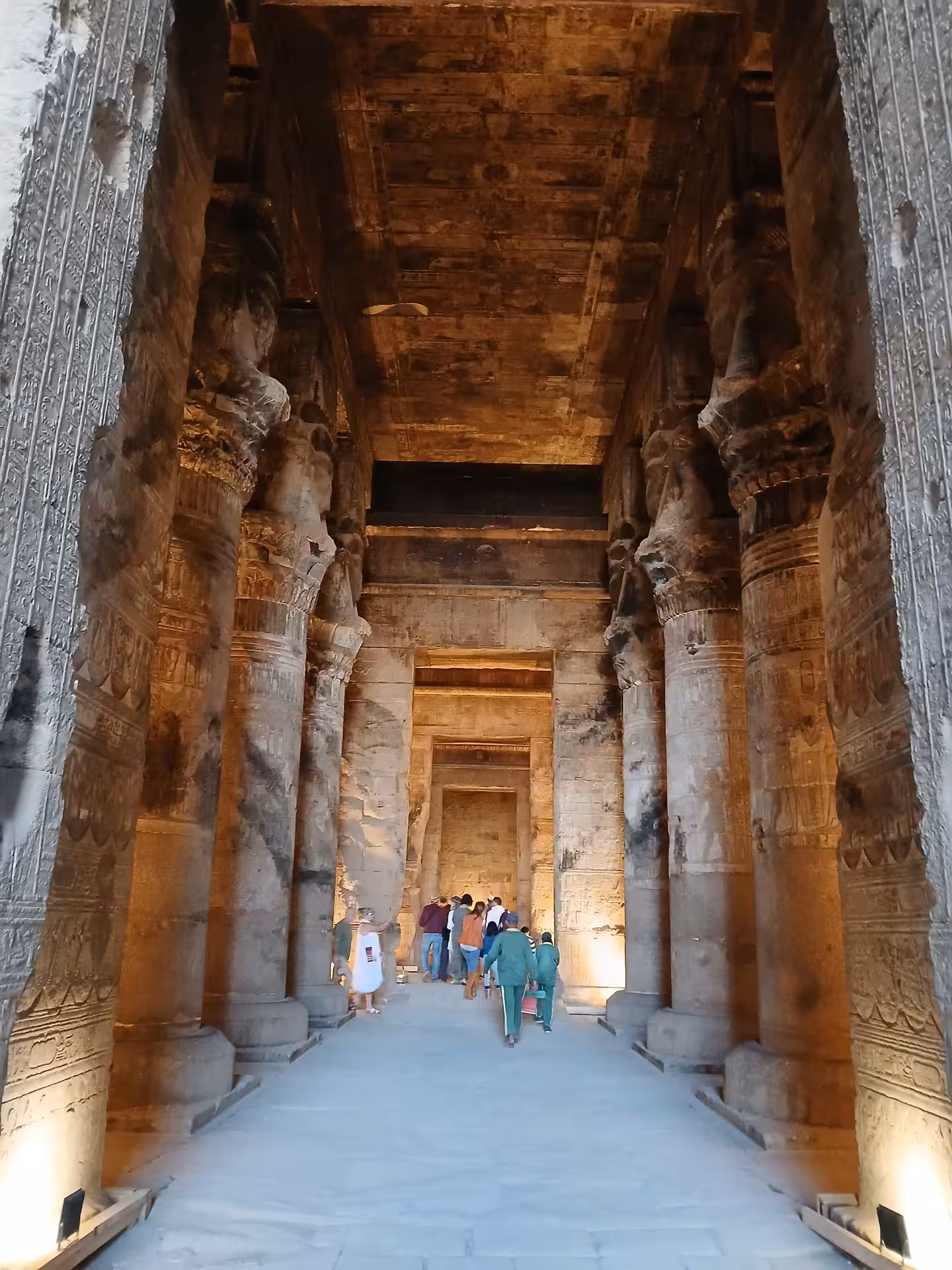Walk through the grand, columned halls of a historic Egyptian temple, illuminated by warm lighting.