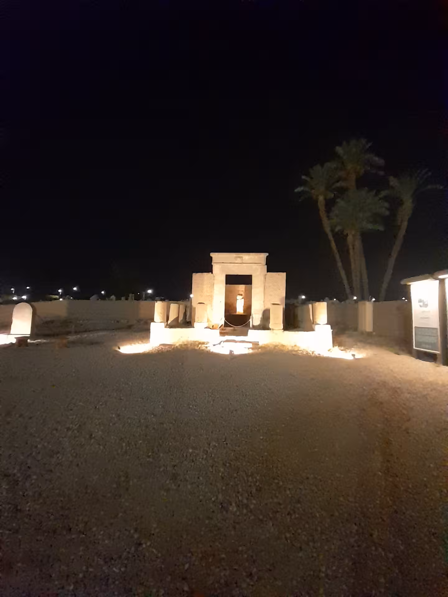 Illuminated Egyptian temple entrance at night, surrounded by palm trees, perfect for a mystical adventure in Egypt.