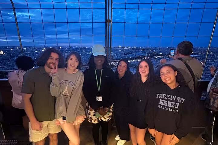Group photo on the Eiffel Tower viewing platform at dusk during a luxury private Paris tour with Seine cruise
