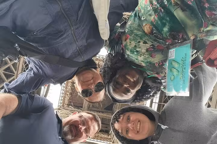 Group selfie under the Eiffel Tower during private Paris tour with luxury lunch, Seine cruise and Louvre